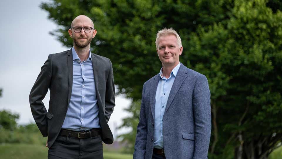 Ian Hodgkinson and Tom Jackson standing outside with trees in the background.