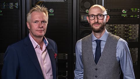 Professors Tom Jackson and Ian Hodgkinson dressed smartly standing in front of a data centre.