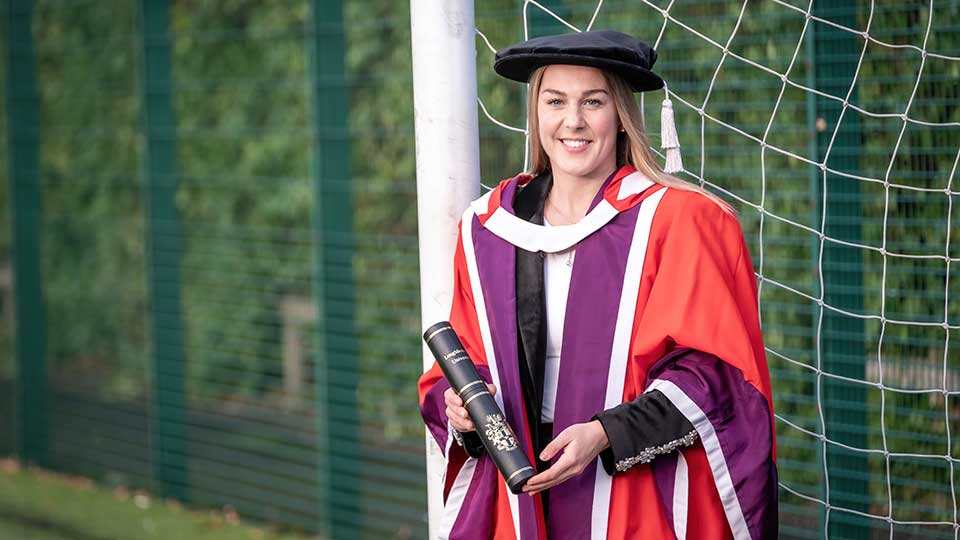 Mary Earps in graduation robes holding her honorary degree.