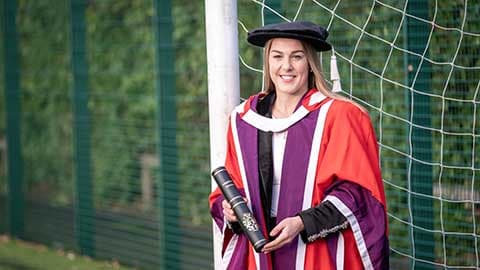 Mary Earps in graduation robes holding her honorary degree.