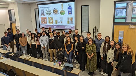 Staff and students standing in a row in a lecture theatre.