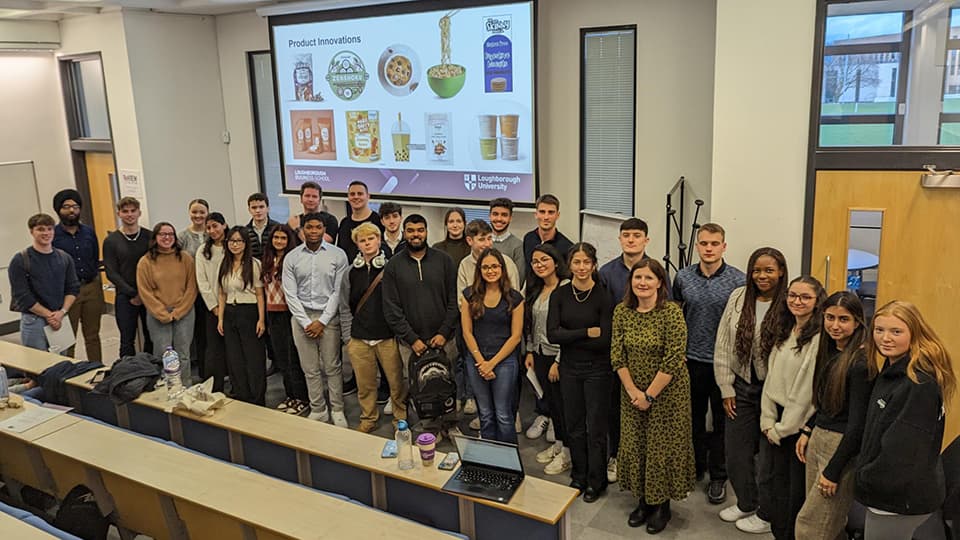 Staff and students standing in a row in a lecture theatre.