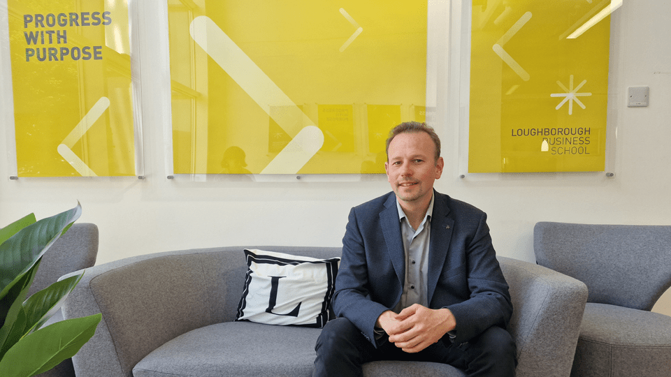 Dr Klaus Friesenbichler sits on a sofa in Loughborough Business School.