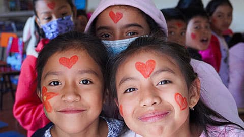 School children in Guatemala that have had their faces painted with heart and flower shapes.