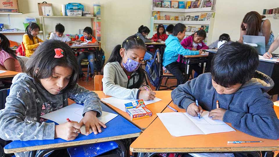 School children in Guatemala drawing using crayons in the classroom.