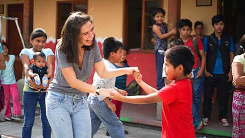 Volunteers and school children dancing together in a school playground.
