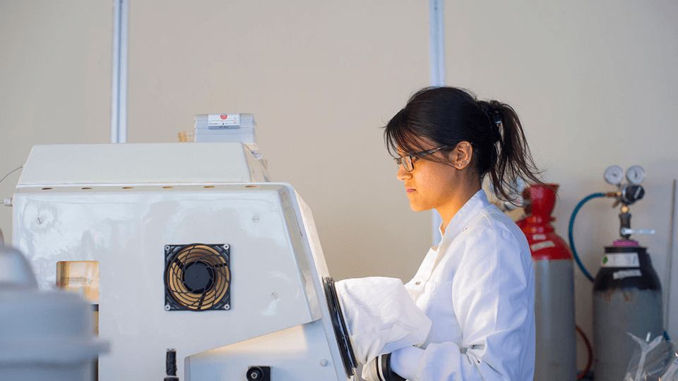 female student in lab coat working with machine