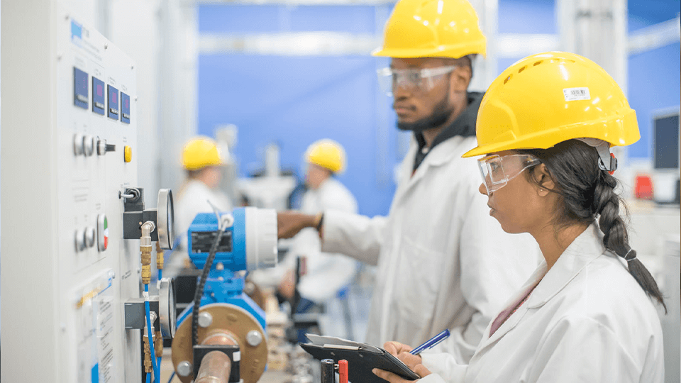 image of 2 students in yellow hats working in a macine