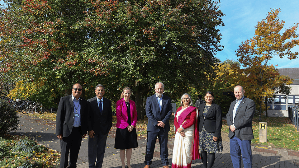 group picture with Dr Kanitkar and staff with trees in background