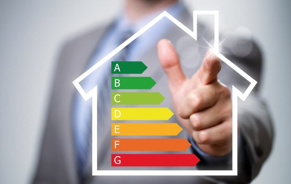 an illustration of the building energy rating scale (A - G ratings) on a clear overlay with a person standing in the background pointing towards it