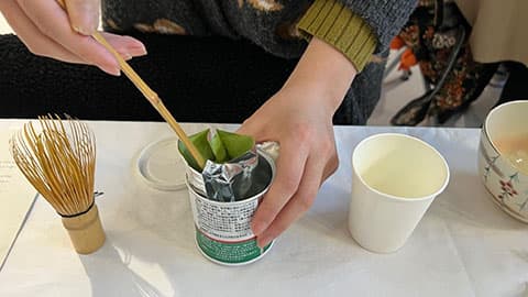 close up of a student's hands preparing a traditional Japanese drink
