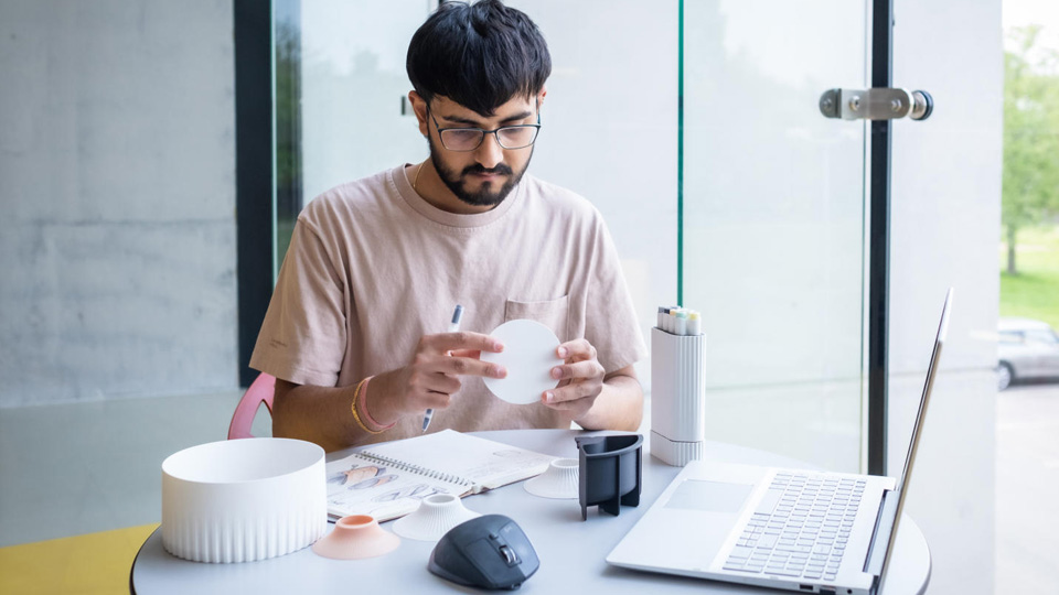 A student sitting at a desk and working on their designs