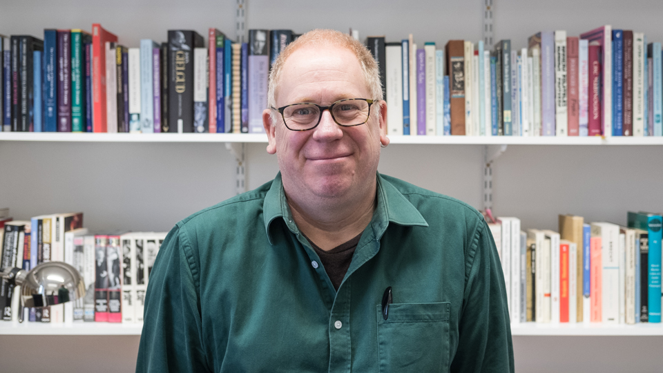 Mike Wilson smiling at the camera with books in the background