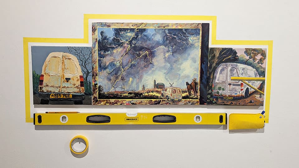Three paintings of different sizes mounted on a wall with yellow tape surrounding them and a spirit level positioned below