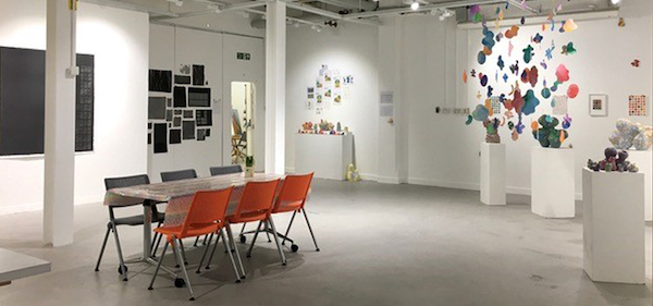 a room with an exhibition of art and table and chairs
