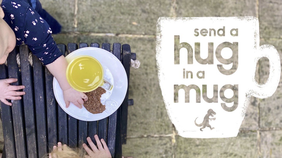 the Hug in a Mug logo with 2 children eating cookies
