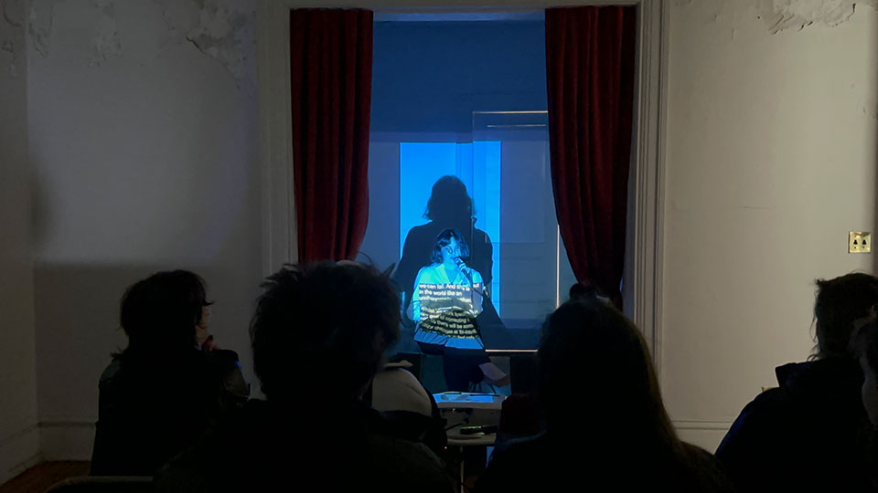 Student stood in front of a projector in front of an audience