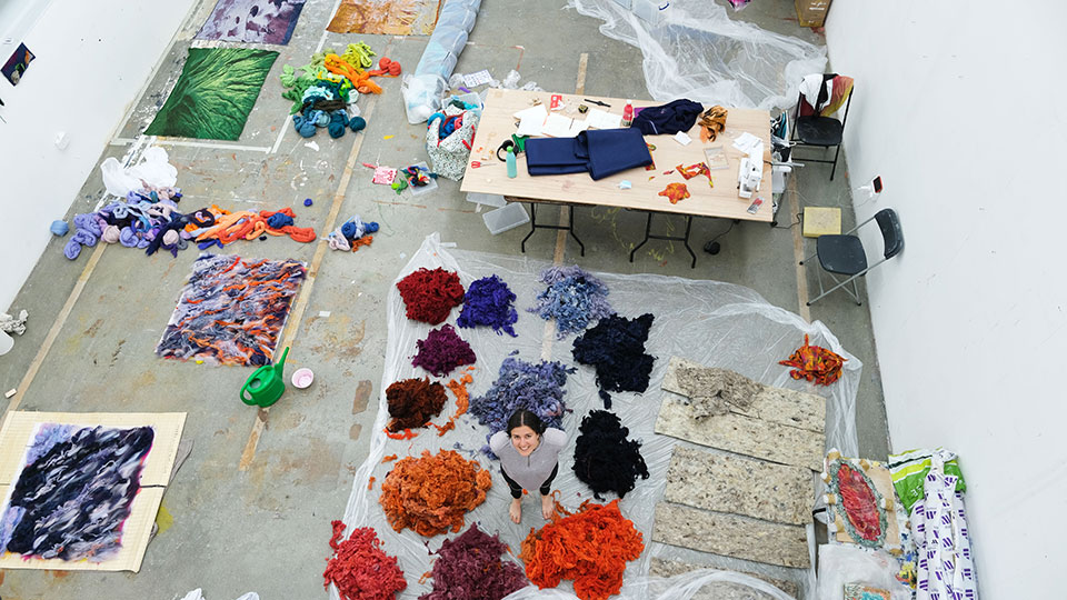 Student in their studio workspace with materials across the room