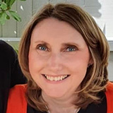 A headshot of Charlotte Holloway wearing a red cardigan