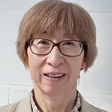 Headshot of Emiko Wilson wearing glasses standing against a plain background