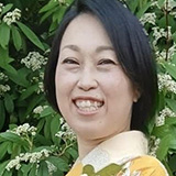 Nao Ozaki standing in front of a bush wearing floral clothing
