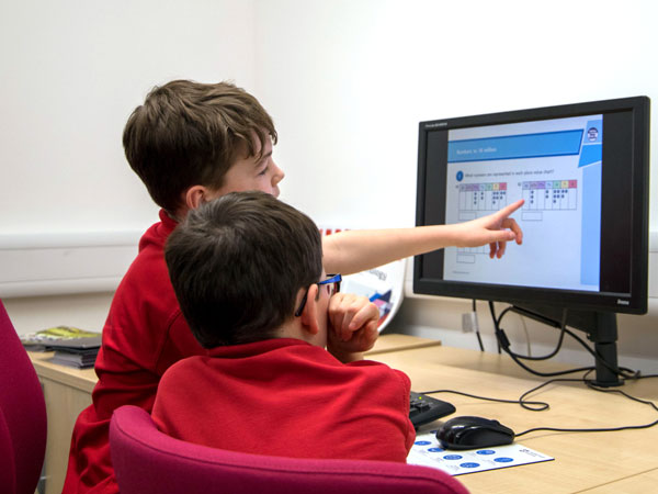 two boys looking at graphs on a computer screen, one of them is pointing
