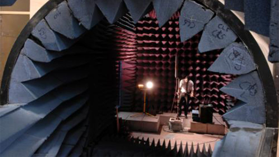 Close up of an anechoic chamber where a male technician can be seen working in the background.