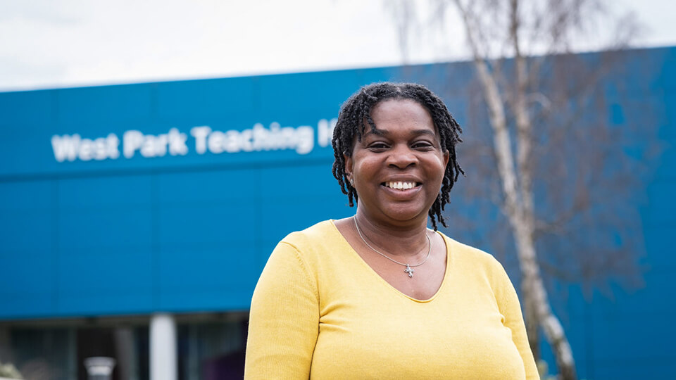 Close up of Dr Sheryl Williams smiling whilst standing in front of West Park Teaching Hub on the engineering side of campus.
