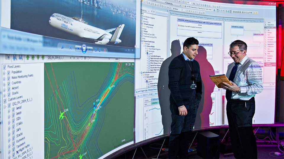 Two male academics standing in front of interactive screens in the Advanced VR research centre.