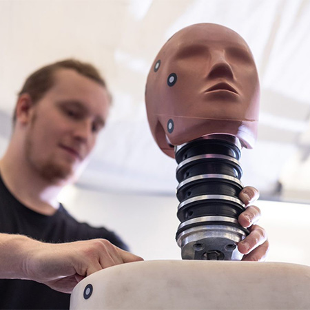 A close-up student holding a human head prototype.