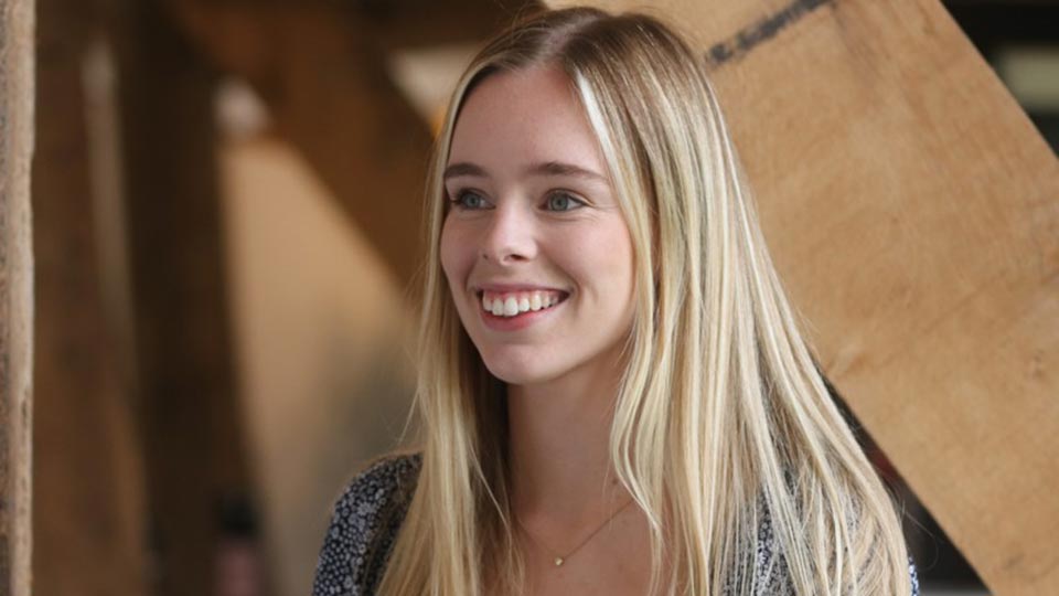 Close-up headshot of Olivia smiling whilst looking away from the camera