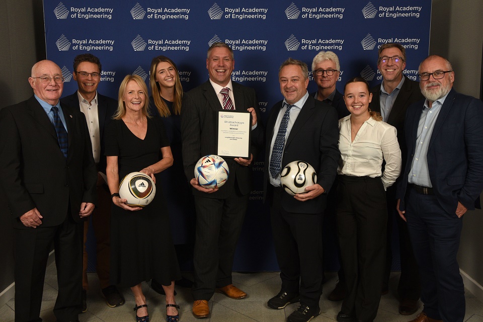 A group from Loughborough University and adidas standing together holding the award and footballs.