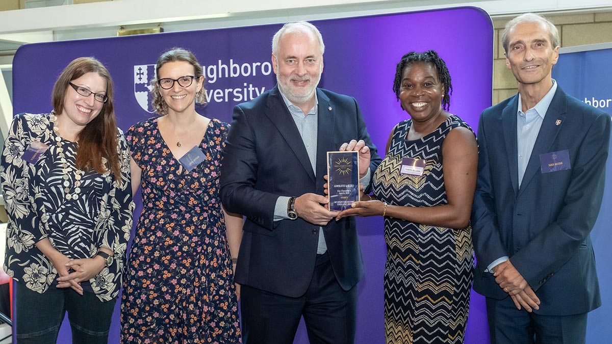 Four academics and the vice-chancellor standing together in a line, looking at the camera, smiling. The vice-chancellor is holding an award plaque.