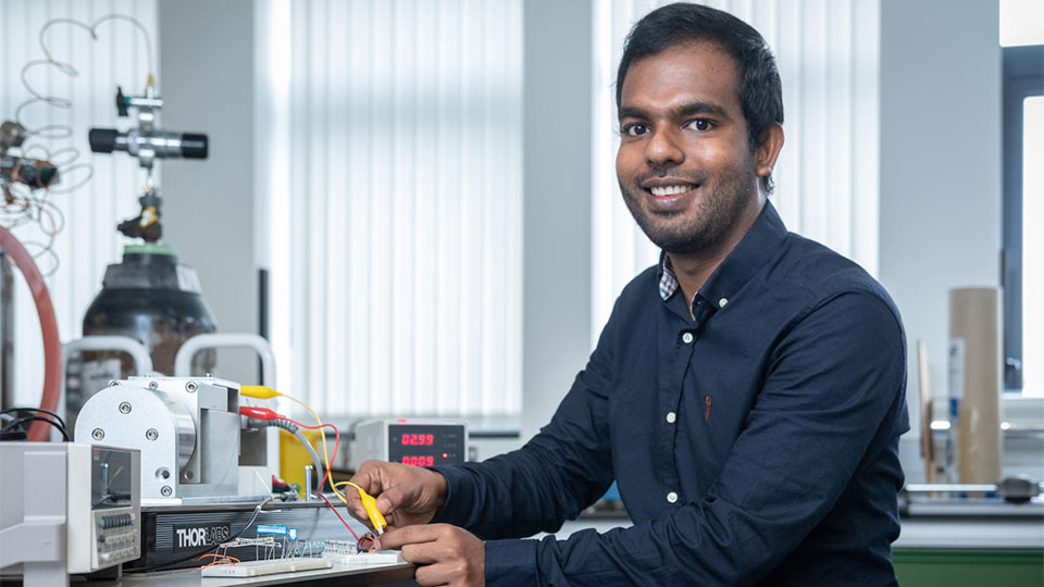 Dr Ishara Dharmesana sat at a worktop in a lab using developing smart textiles powered by body movement for remote health monitoring.