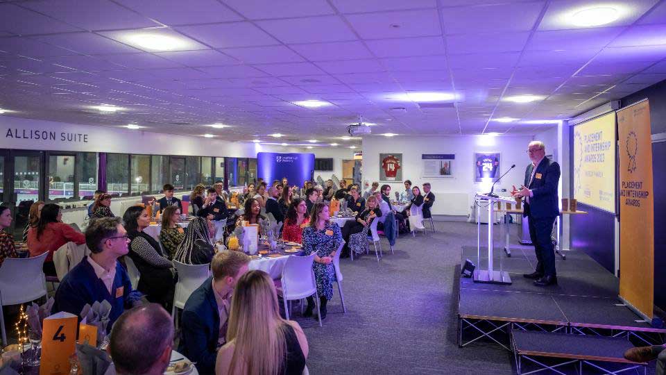 A photo inside the venue shows guests sitting at tables listening to the Vice Chancellor speak on the stage.