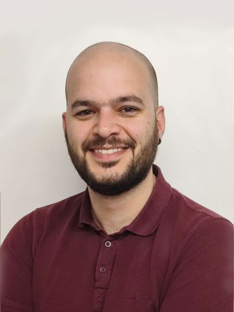 Portrait headshot of Theodoros, smiling, looking directly at the camera against a white background.