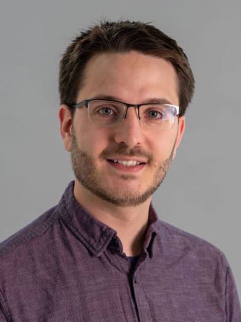 Headshot of Ben Clark with a grey background.