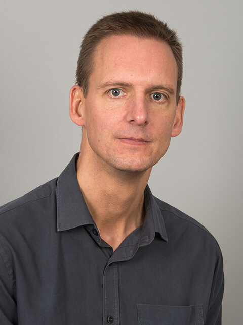 A Headshot of Kevin featured on a grey background.