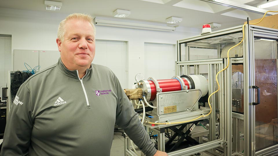 Dr Paul Sherratt standing in a lab in the Sports Technology Institute where equipment is featured in the background. 