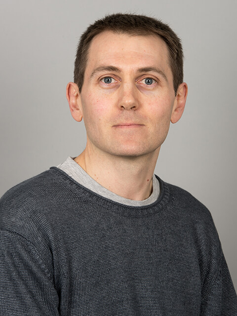 Headshot of Tom with a grey background