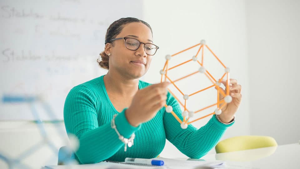 A student in the Mathematical Sciences department observing a physical shape structure.