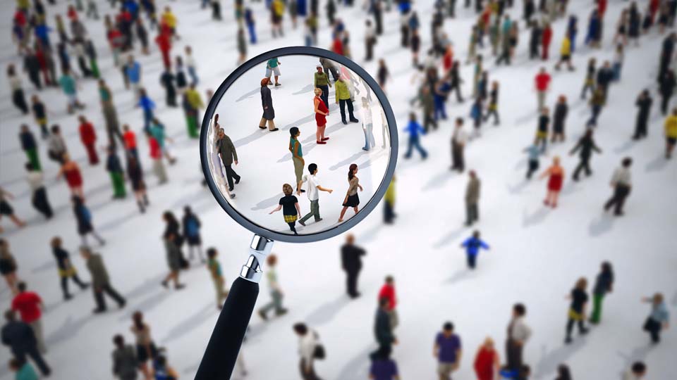 A wide angle view of a crowd with a magnifying glass zooming in on a section of people.