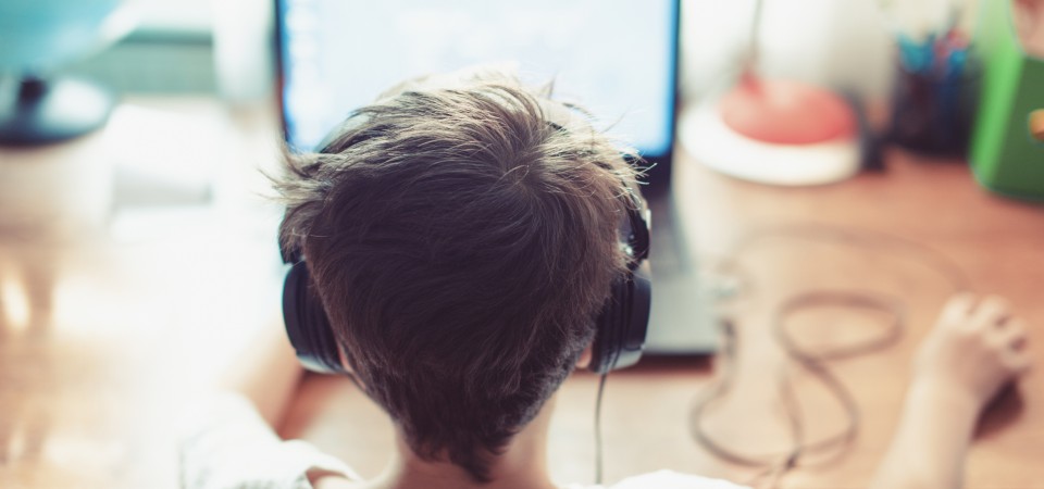 a boy wearing headphones looking at a laptop