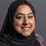 A headshot of Yesmin Choudhury against a grey background
