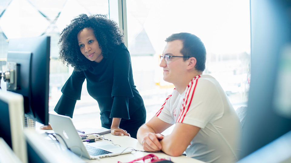 Two people reviewing work on a computer screen