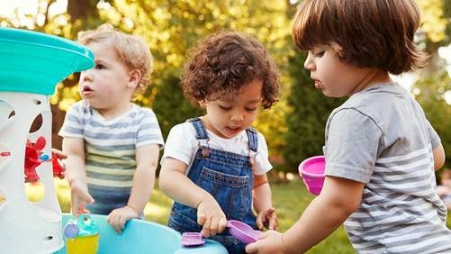 a group of young children playing with toys outdoors