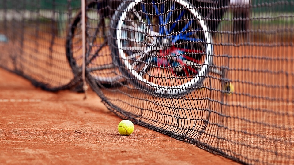 a tennis ball and tennis net with a wheelchair in the background