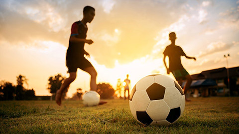 Children playing football in the setting sun. Image provided by Getty.