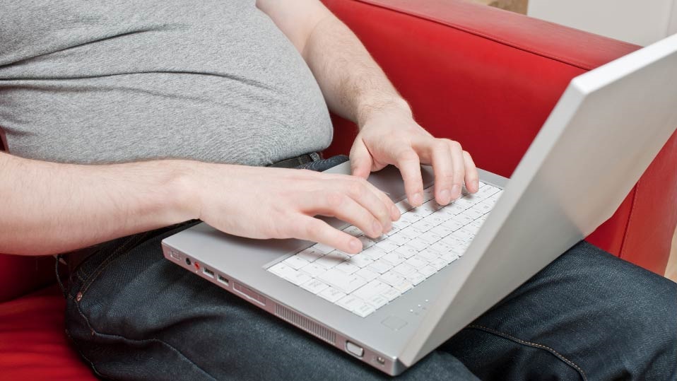 a close up of a person sitting on a sofa using a laptop computer