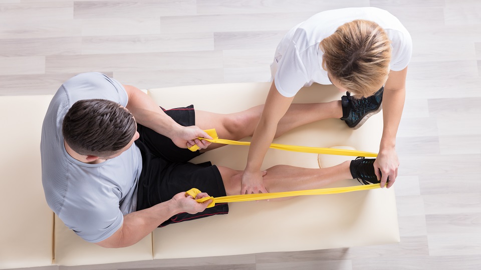 birds-eye view of physiotherapist with patient working on an exercise using a rubber band on patient's leg